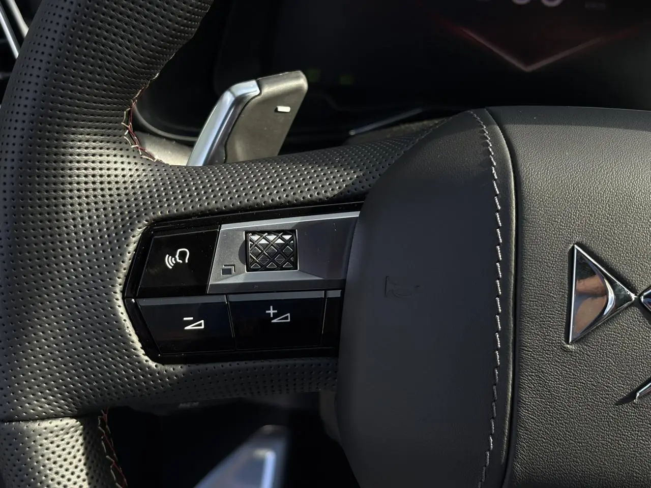 Gros plan sur le volant en cuir perforé noir avec surpiqûres Carmin et commandes multifonctions du DS7 2025.