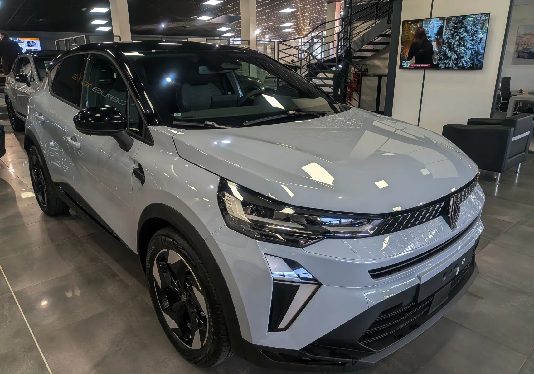 Renault Captur Mild Hybrid gris Rafale avec toit noir, vue 3/4 avant droit en showroom lumineux.