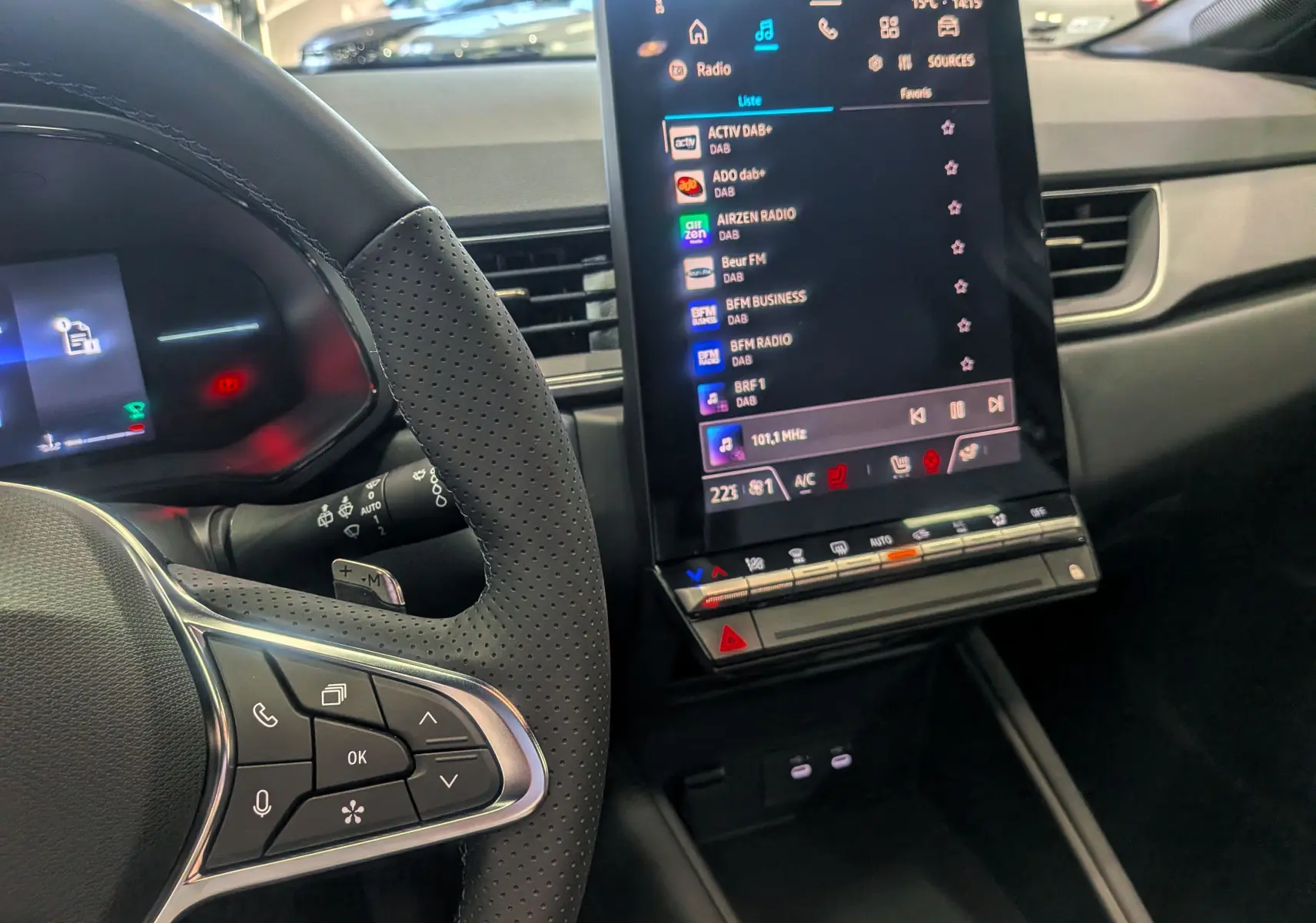 Vue rapprochée de l’intérieur du Renault Captur 2025, avec volant perforé et écran tactile central affichant la radio.