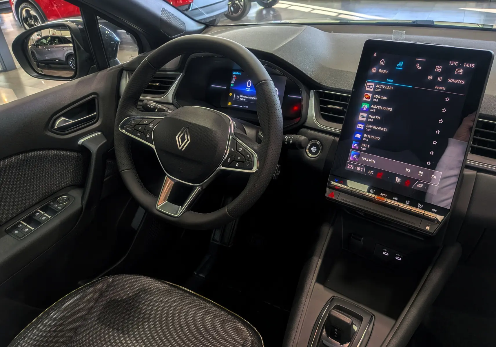 Vue intérieure côté conducteur du Renault Captur 2025, volant multifonction et grand écran tactile central allumé.