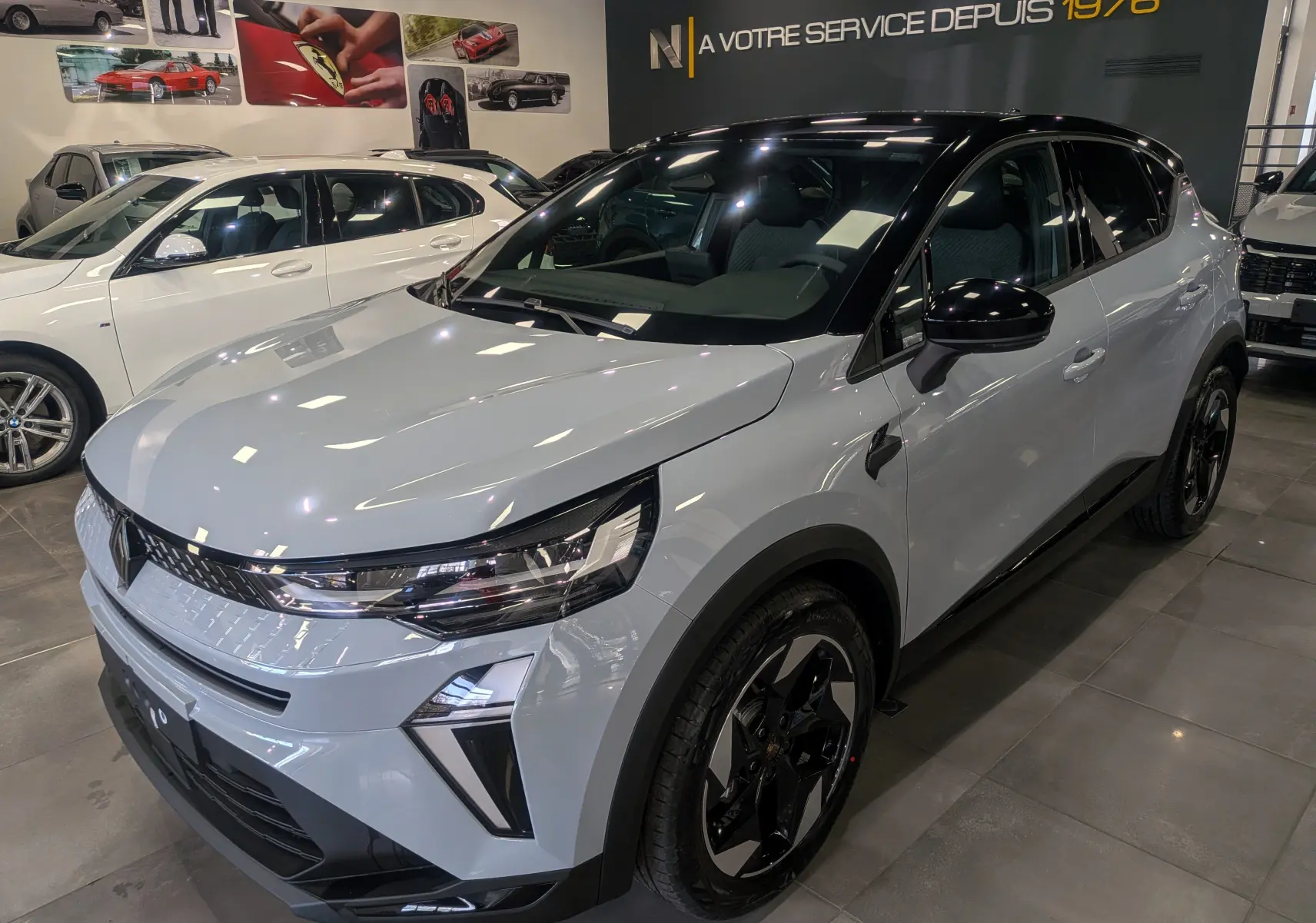 Renault Captur Mild Hybrid 2025 gris Rafale avec toit noir, vue 3/4 avant droit en showroom lumineux.