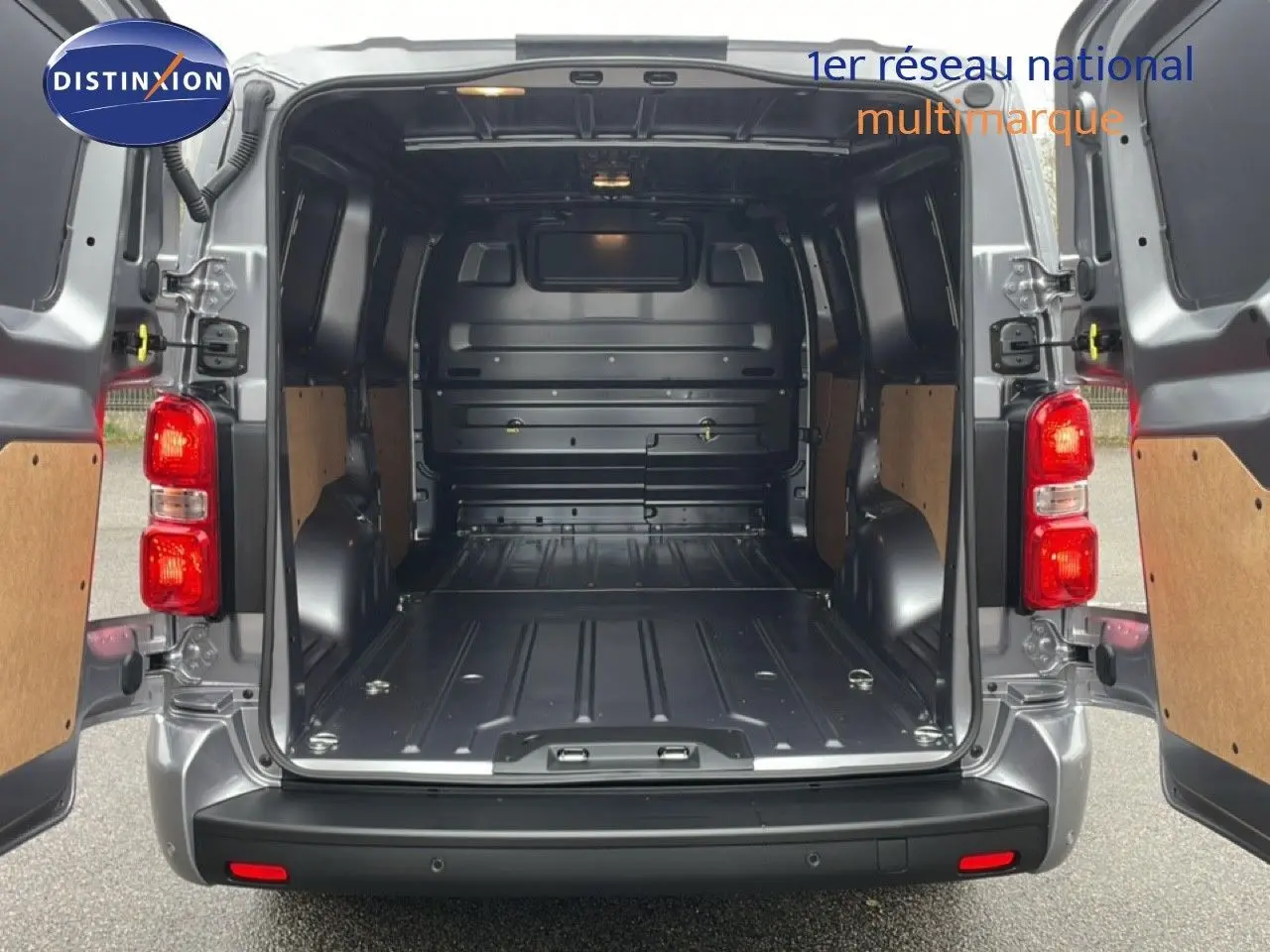 Vue arrière du Citroën Jumpy gris Artense avec portes ouvertes montrant l’espace de chargement vide et les panneaux boisés.