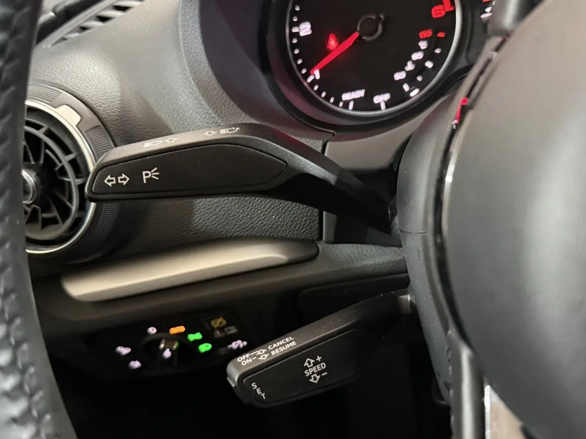 Vue rapprochée du volant noir et des commandes de clignotants et régulateur de vitesse d’une Audi A3 bleu 2018.