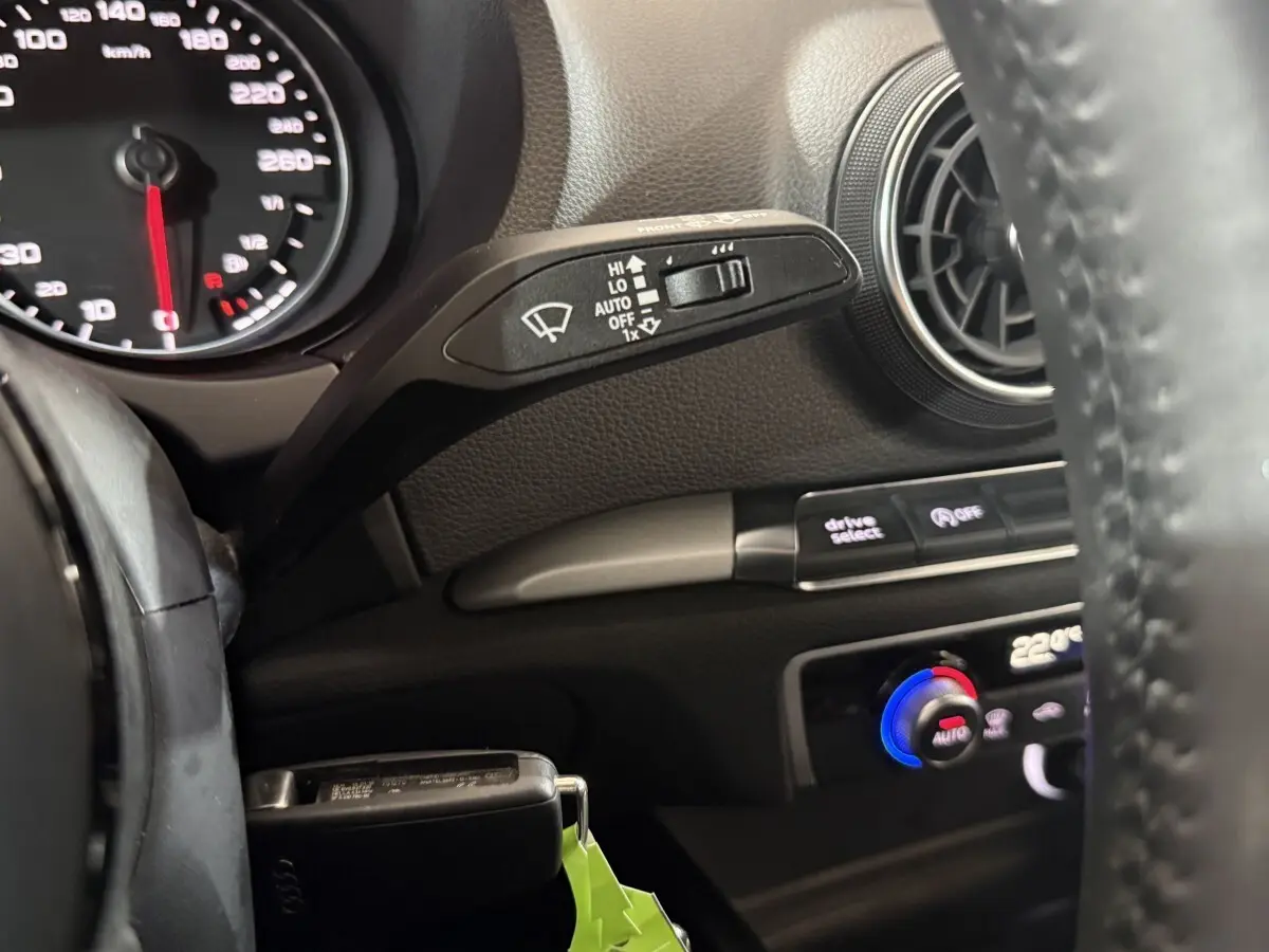Détail intérieur côté gauche d'un Audi A3 bleu 2018, montrant commandes essuie-glace, ventilation et volant cuir.