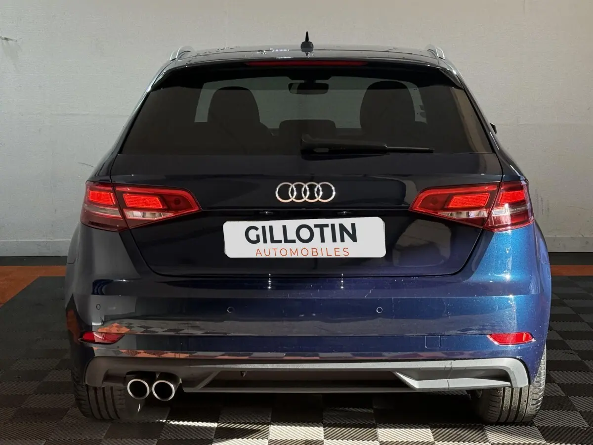 Vue arrière d'une Audi A3 2.0 TDI Business Line bleu foncé avec double sortie d'échappement et feux LED allumés.