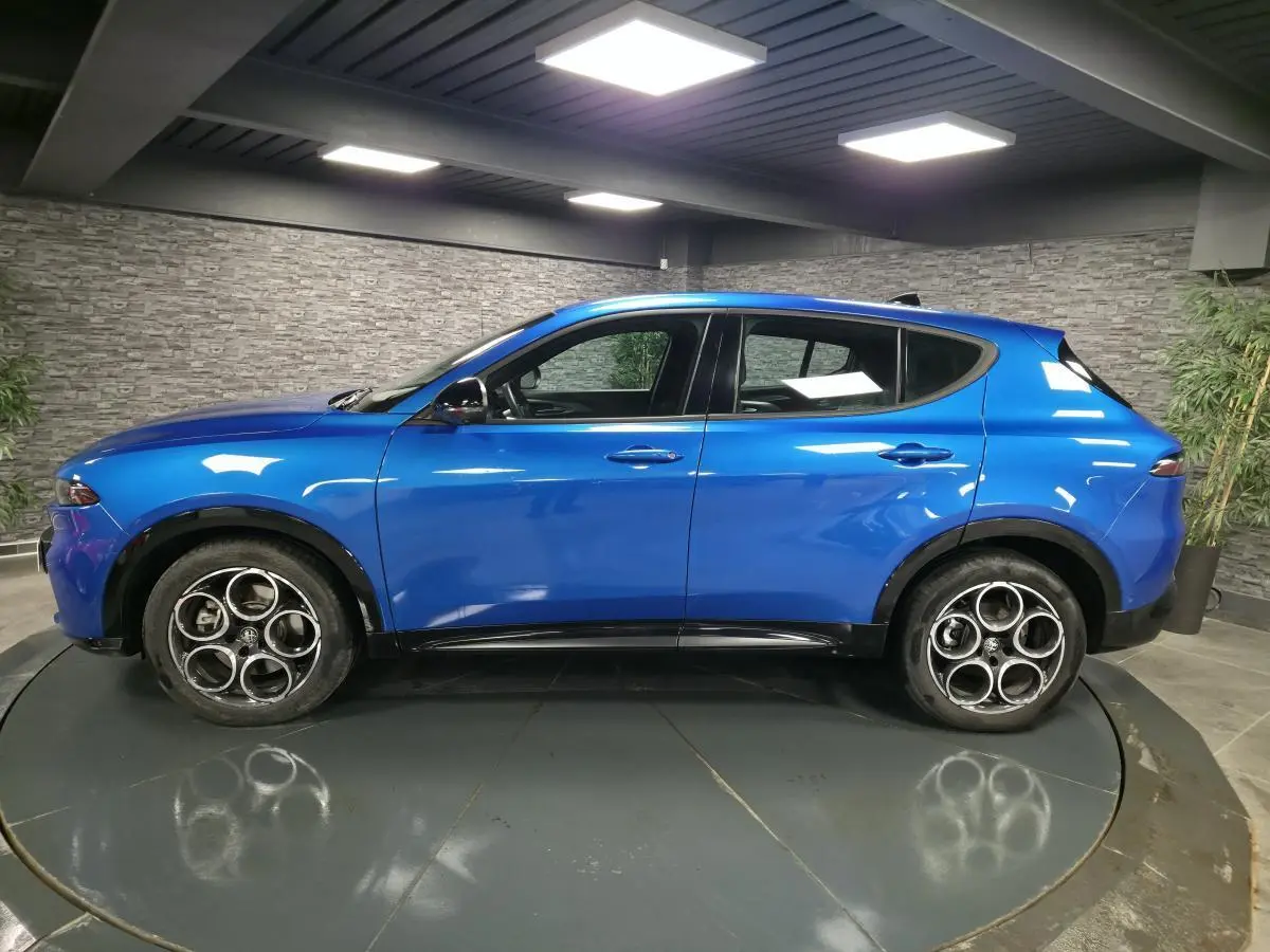 Vue latérale droite d'un Alfa Romeo Tonale bleu métallisé avec jantes alliage 18 pouces et détails noirs brillants.