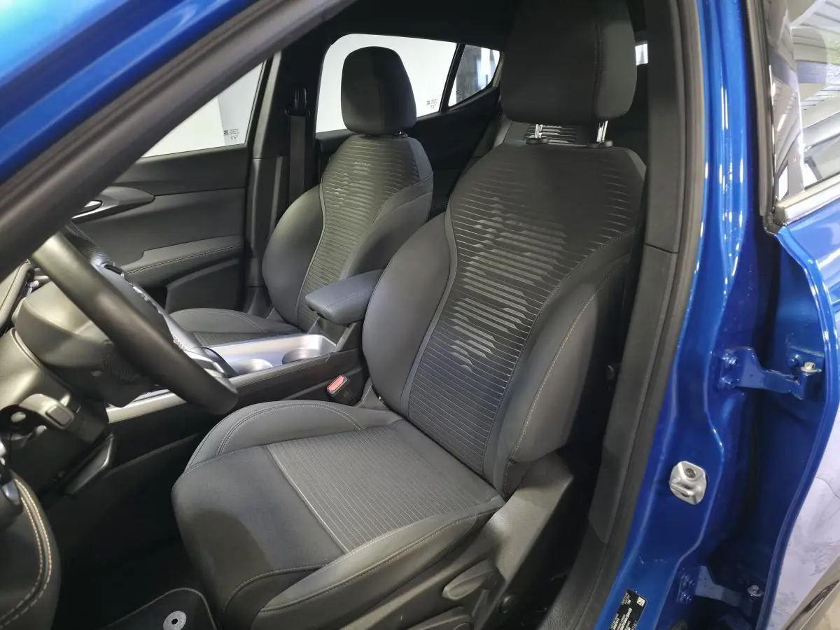 Vue intérieure côté conducteur de l'Alfa Romeo Tonale bleu 2025, sièges tissu noir avec surpiqûres beige et accoudoir central.