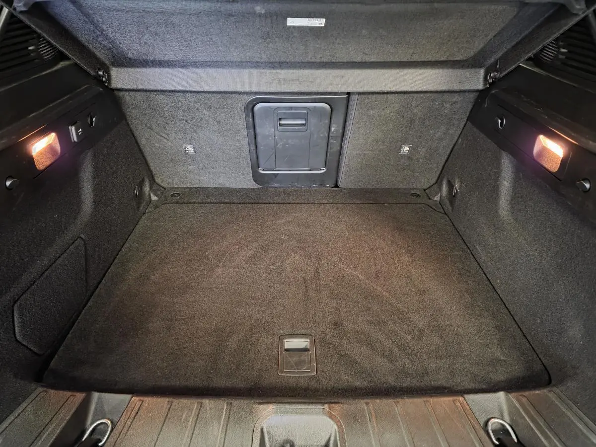Coffre spacieux de l'Alfa Romeo Tonale 2025, vue intérieure arrière avec éclairage et revêtement noir.