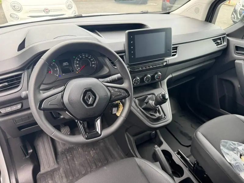 Vue intérieure avant du Renault Kangoo blanc 2024, volant multifonction, écran tactile et boîte manuelle visible.