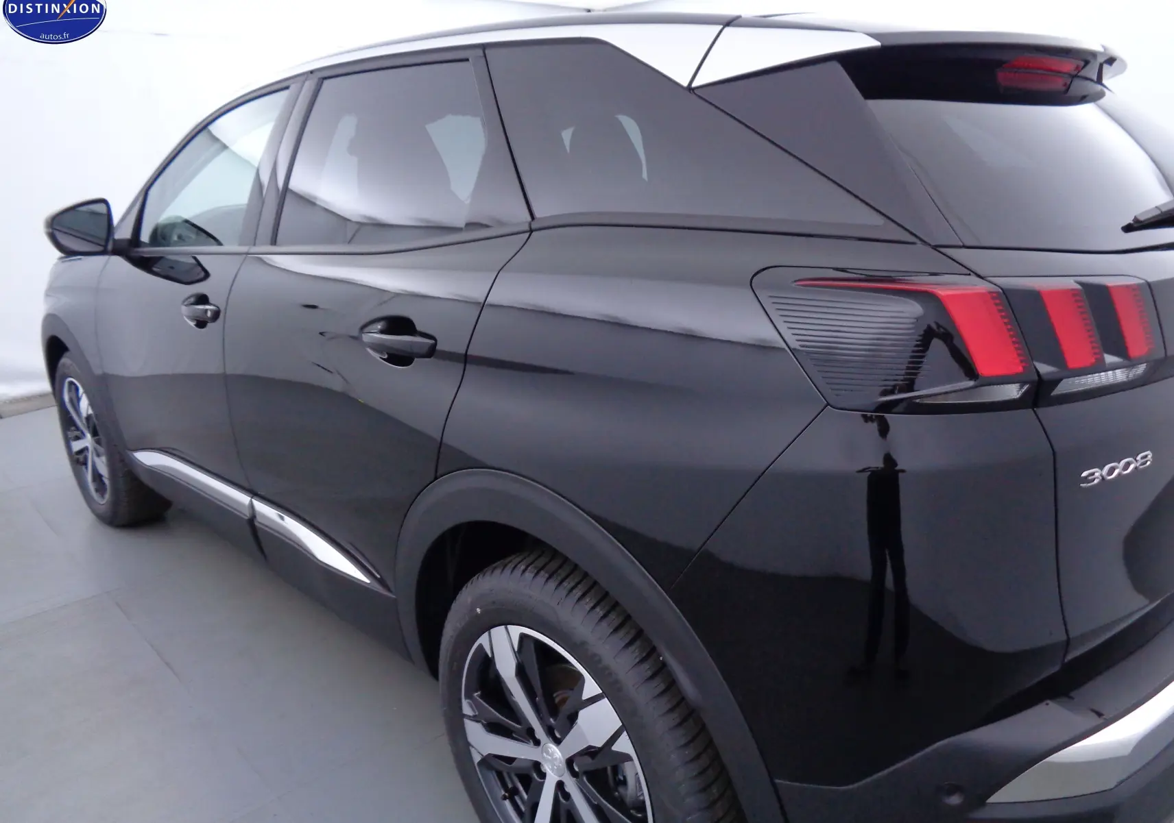 Vue 3/4 arrière droite du Peugeot 3008 noir perle métal avec feux arrière à griffes distinctifs et jantes biton.