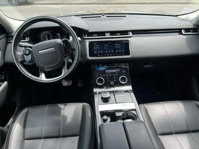 Intérieur noir du Range Rover Velar 2018, vue du tableau de bord et console centrale avec écran tactile et volant multifonction.