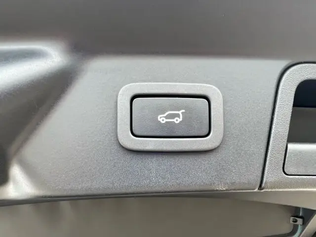Bouton noir avec pictogramme blanc d'ouverture de coffre, situé à l'intérieur du Range Rover Velar 2018.