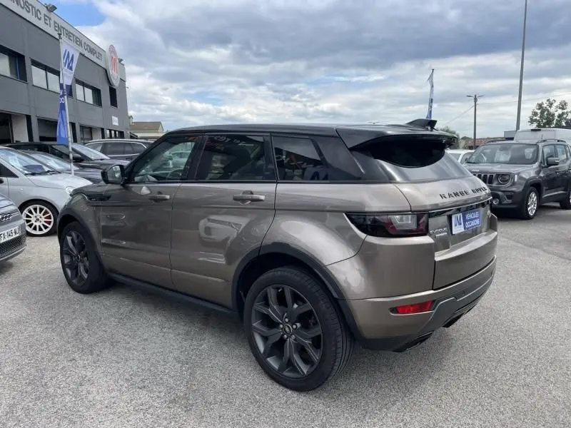 Vue 3/4 arrière droite d'un Range Rover Evoque TD4 180 Autobiography 2017 en marron métal avec toit noir.
