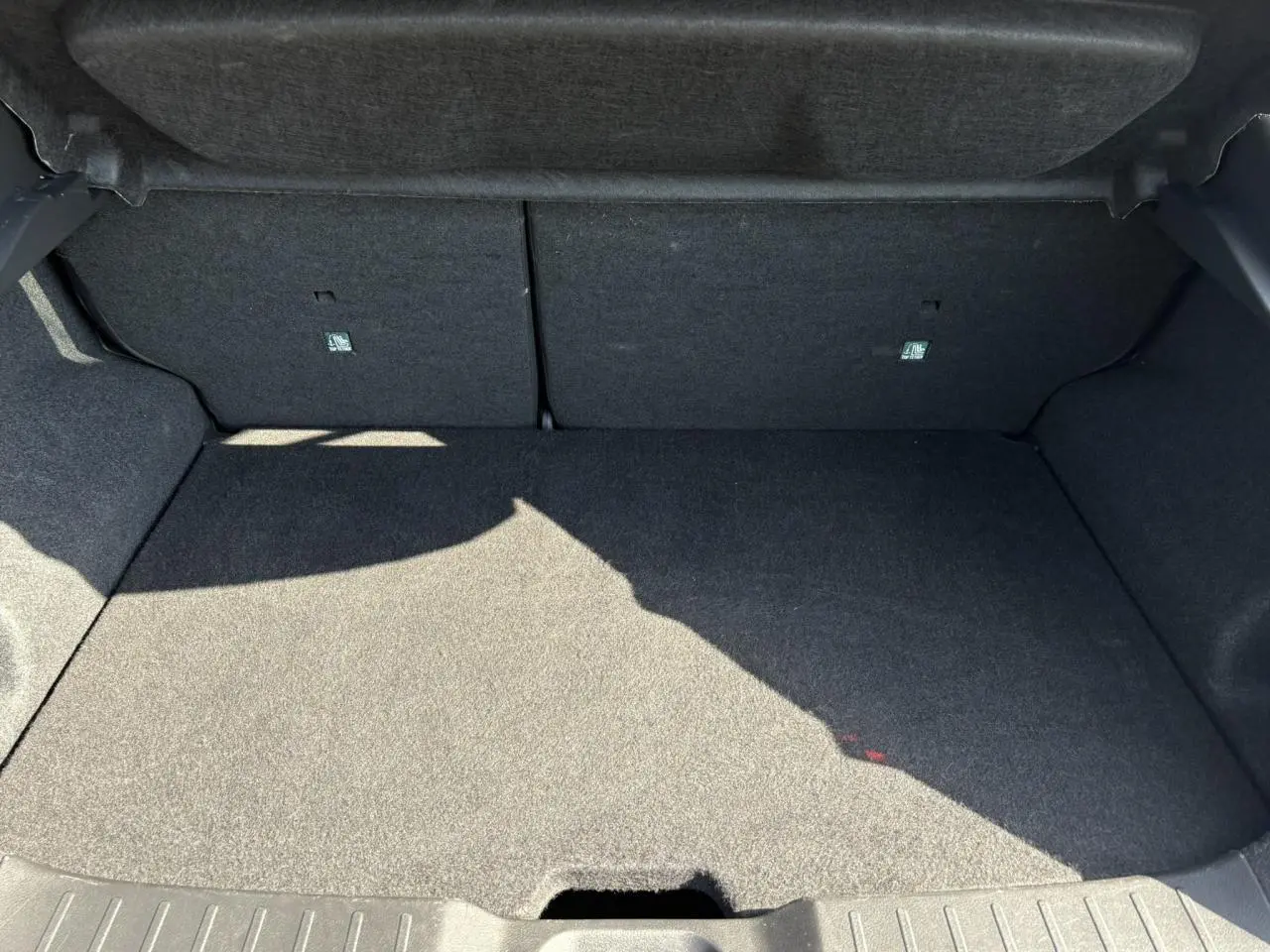 Coffre spacieux et vide du Nissan Juke 2024 gris Dark Metal, vue intérieure arrière avec banquette rabattable.