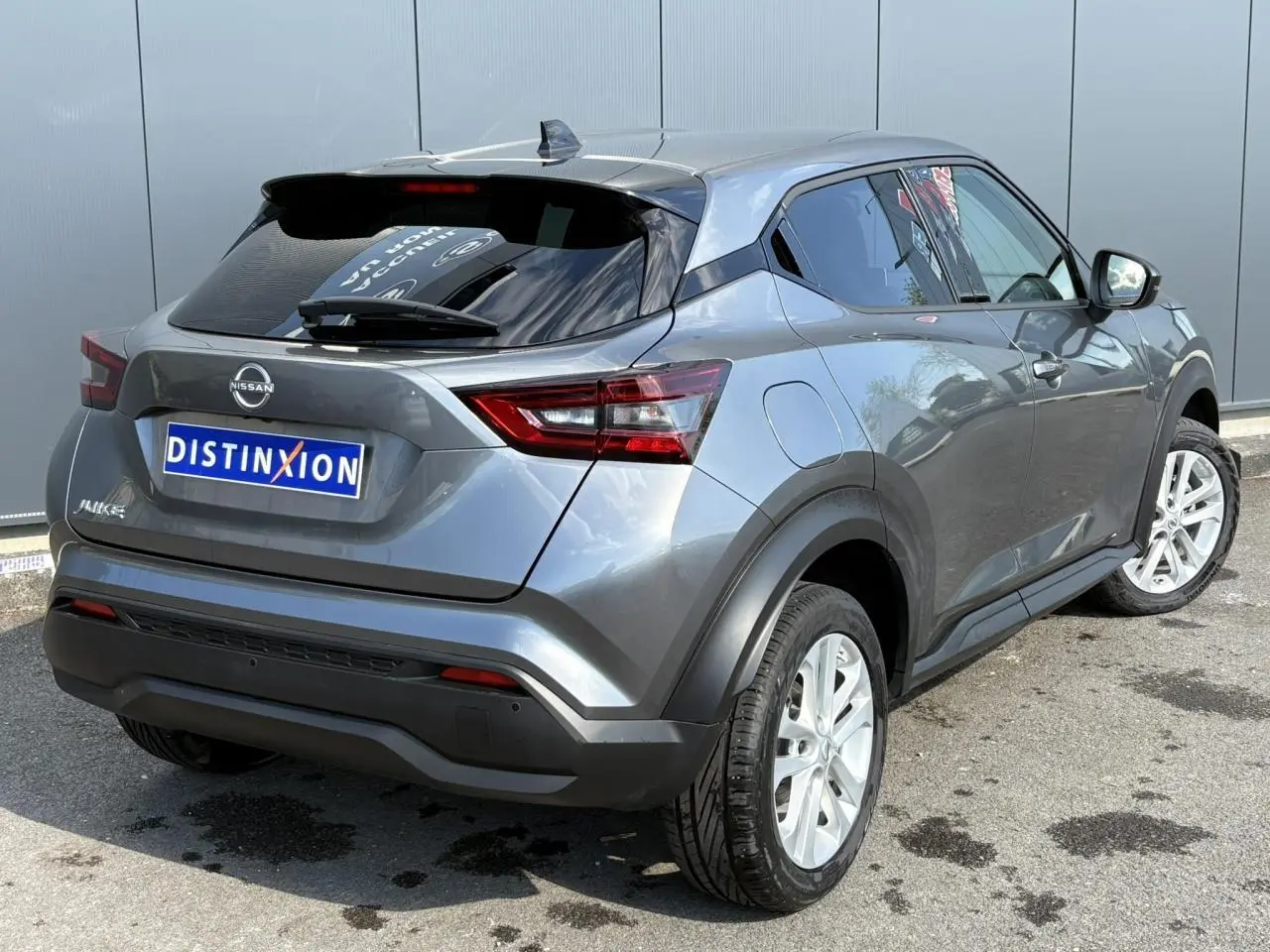 Nissan Juke gris Dark Metal vu en 3/4 arrière droit, avec jantes alliage et vitres teintées.