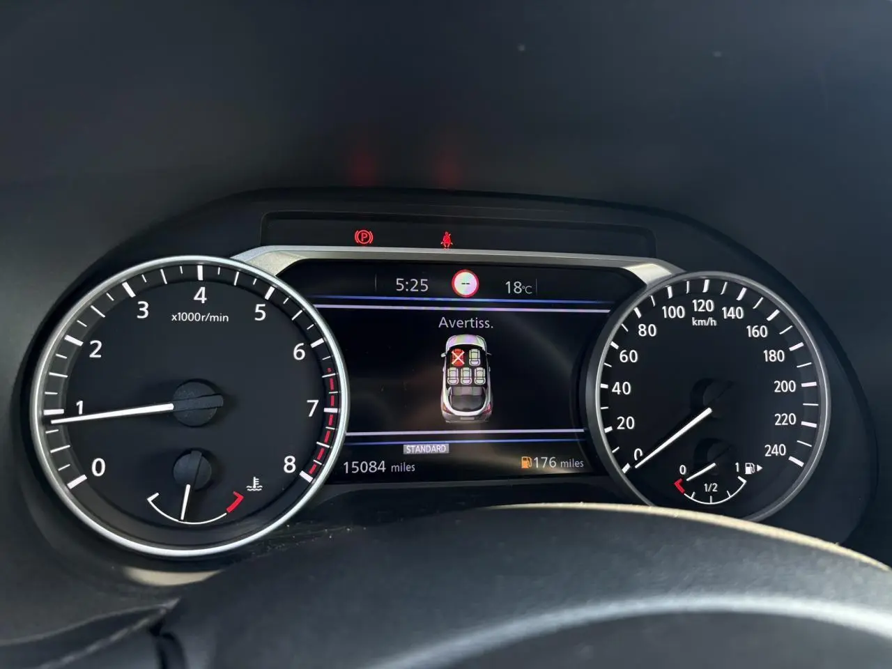 Vue rapprochée du tableau de bord du Nissan Juke 2024, affichant les compteurs et un avertissement sur l'écran central.