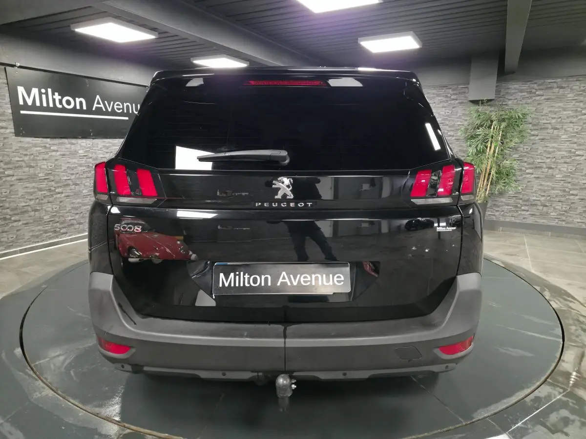 Vue arrière d'un Peugeot 5008 noir 2021 avec attelage, dans un showroom intérieur.