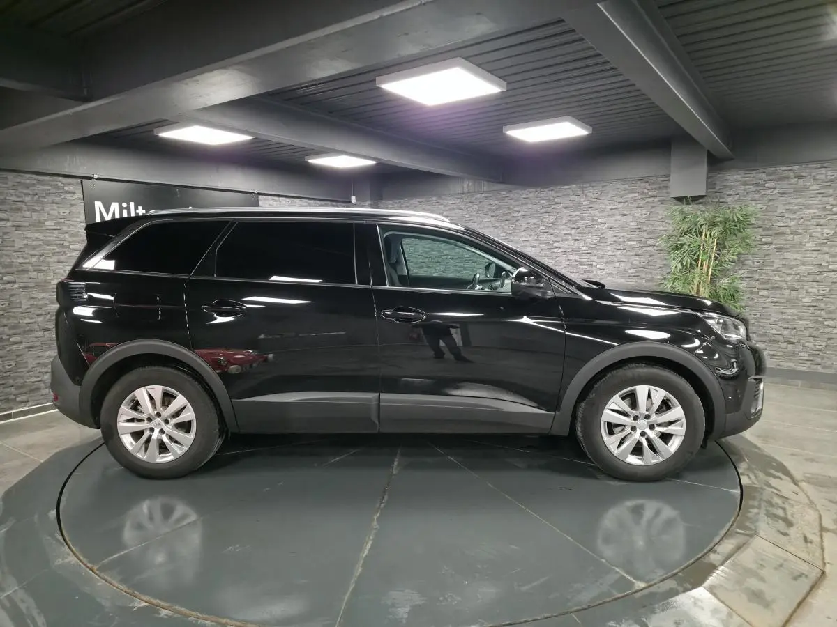 Profil droit d'un Peugeot 5008 noir métallisé 2021, avec jantes alliage 17 pouces et vitres teintées.