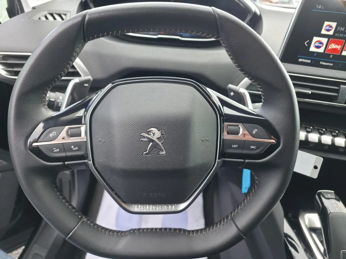 Volant compact en cuir noir du Peugeot 5008 2021 avec commandes intégrées et tableau de bord numérique visible.