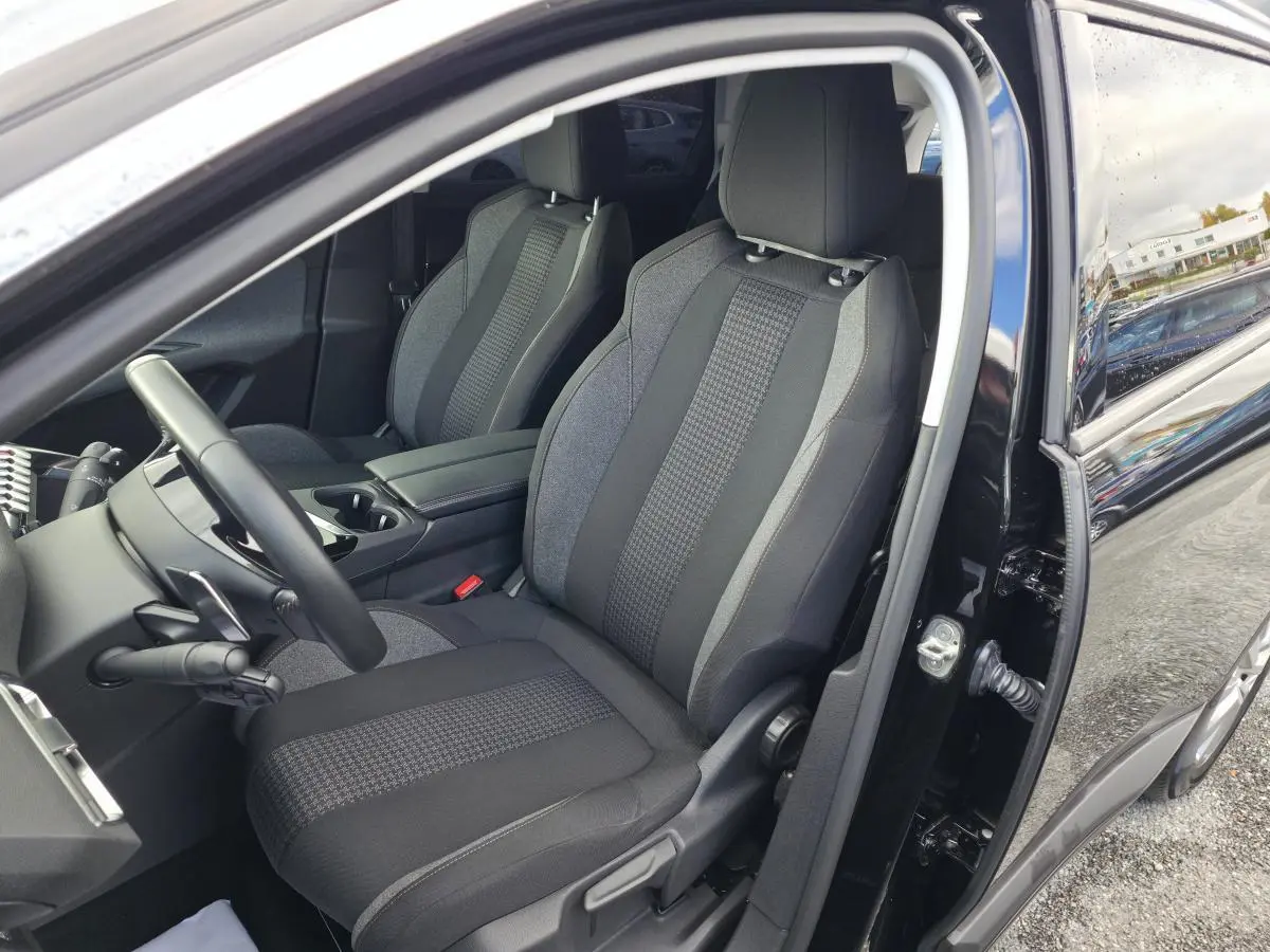 Intérieur côté conducteur du Peugeot 5008 noir 2021, sièges textile gris et noir avec console centrale ouverte.