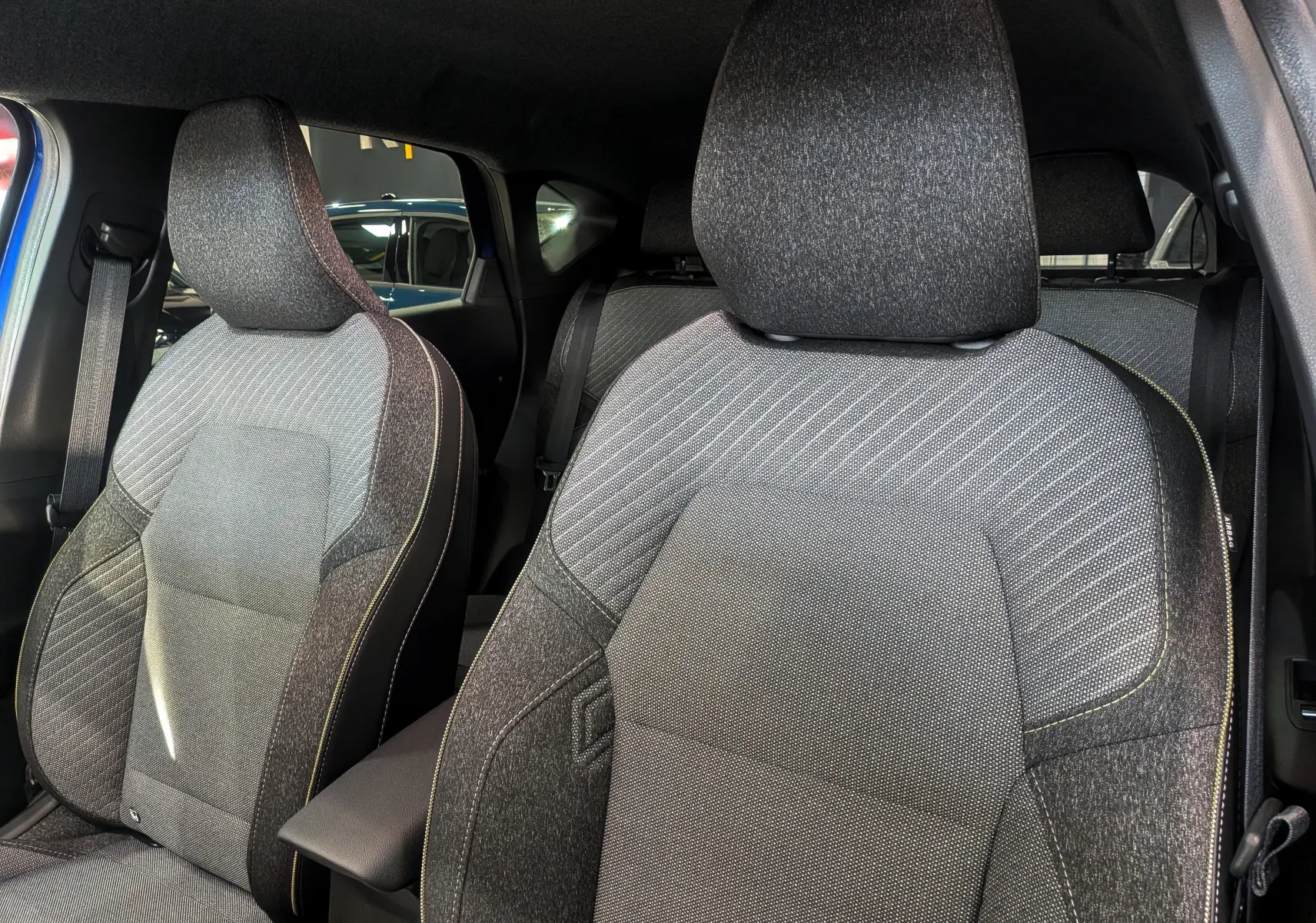 Gros plan sur les sièges avant en tissu gris du Renault Captur 2025, intérieur moderne et épuré.