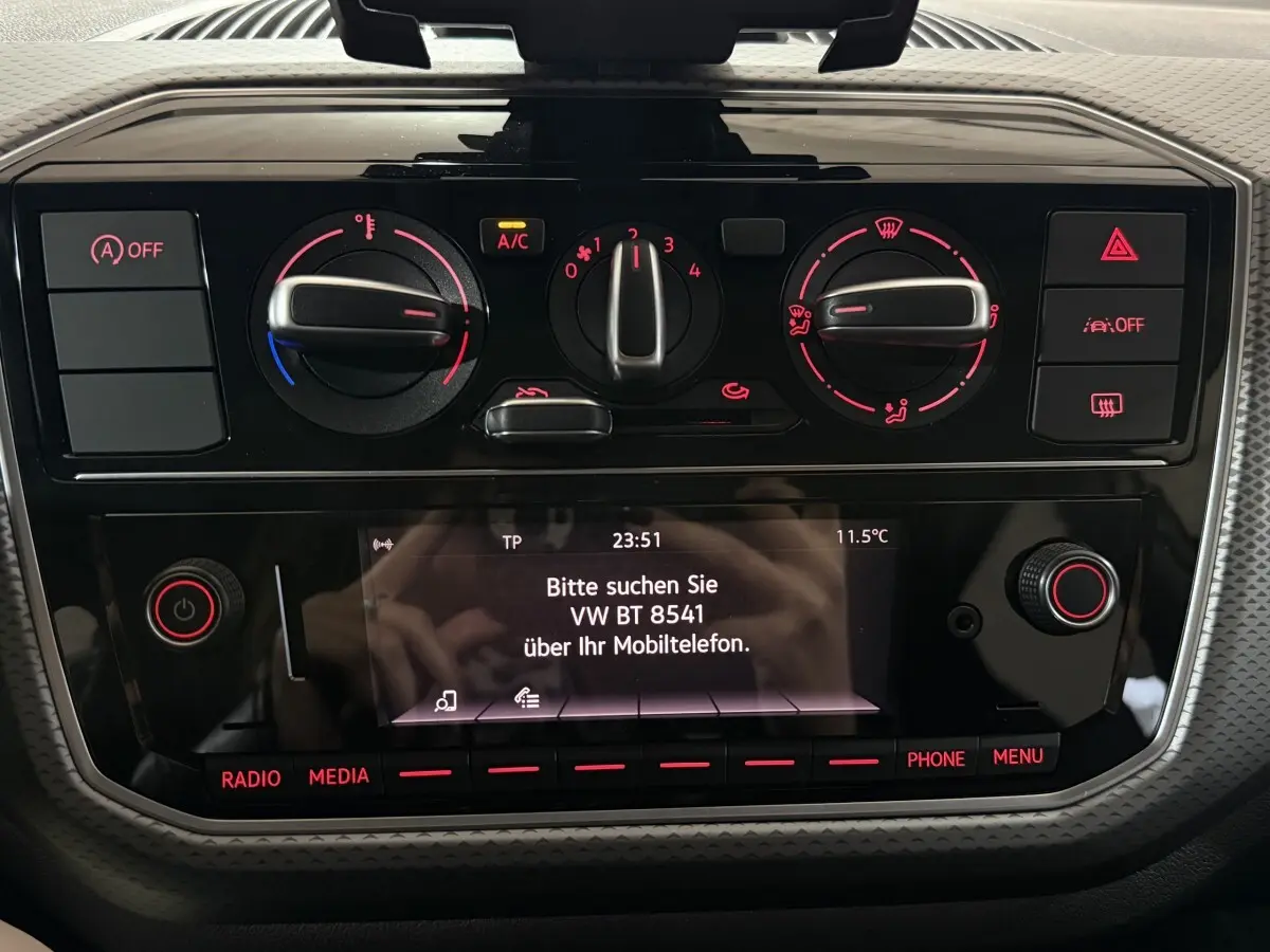 Tableau de bord noir du Volkswagen Up 1.0 65 Active 2022, avec commandes climatisation et écran central allumé.