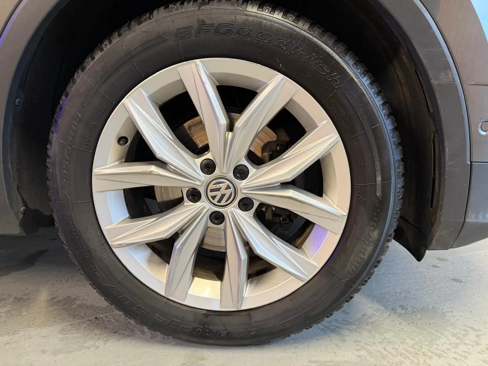 Gros plan sur la jante alu grise avec logo Volkswagen du côté arrière droit du Volkswagen Tiguan gris 2018.