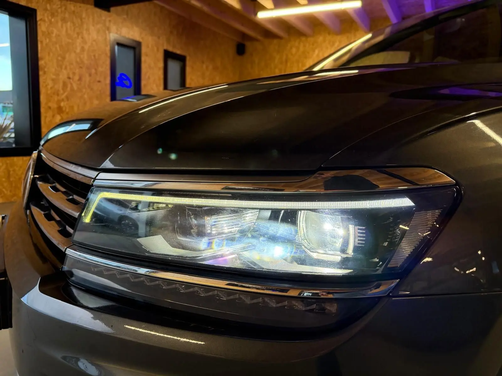 Gros plan sur le phare avant droit du Volkswagen Tiguan gris, mettant en valeur les LED et la calandre chromée.