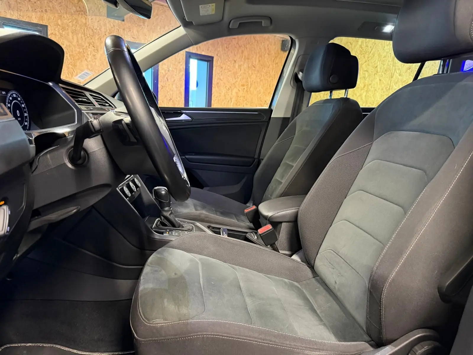 Vue intérieure côté conducteur du Volkswagen Tiguan 2018, sièges sport gris avec volant cuir multifonctions.