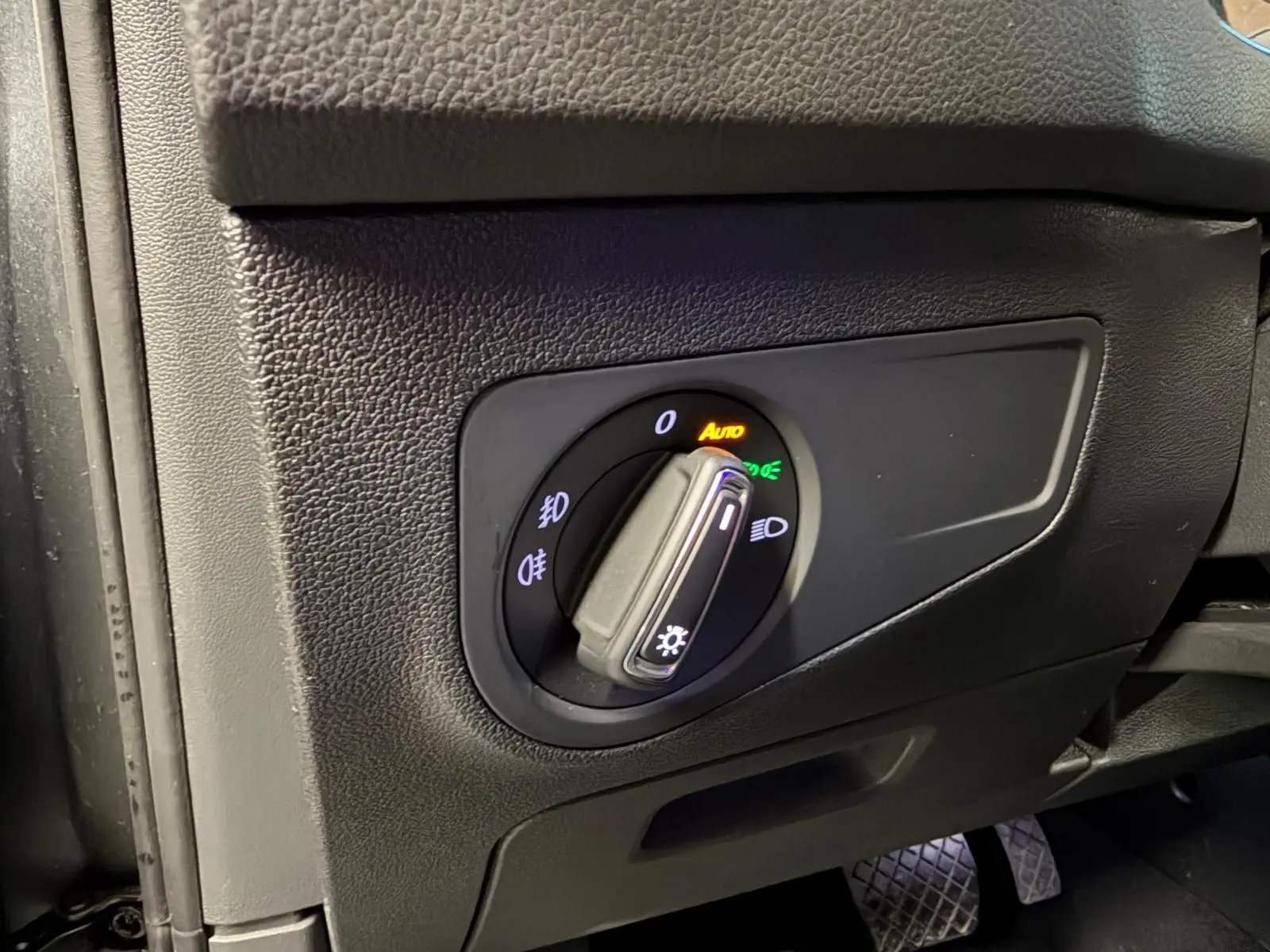 Gros plan sur le bouton de commande des phares dans l'habitacle du Volkswagen Tiguan gris, côté conducteur.
