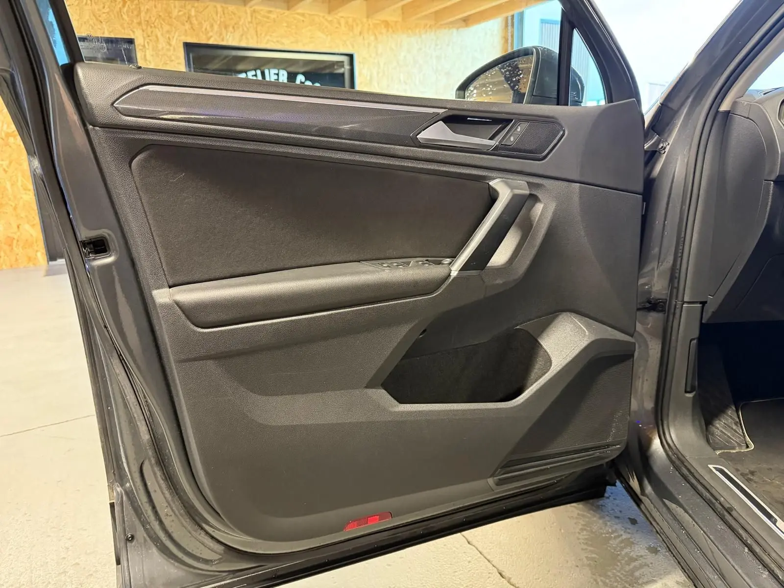 Vue intérieure de la porte avant gauche grise du Volkswagen Tiguan 2018 avec commandes de vitres et poignée argentée.