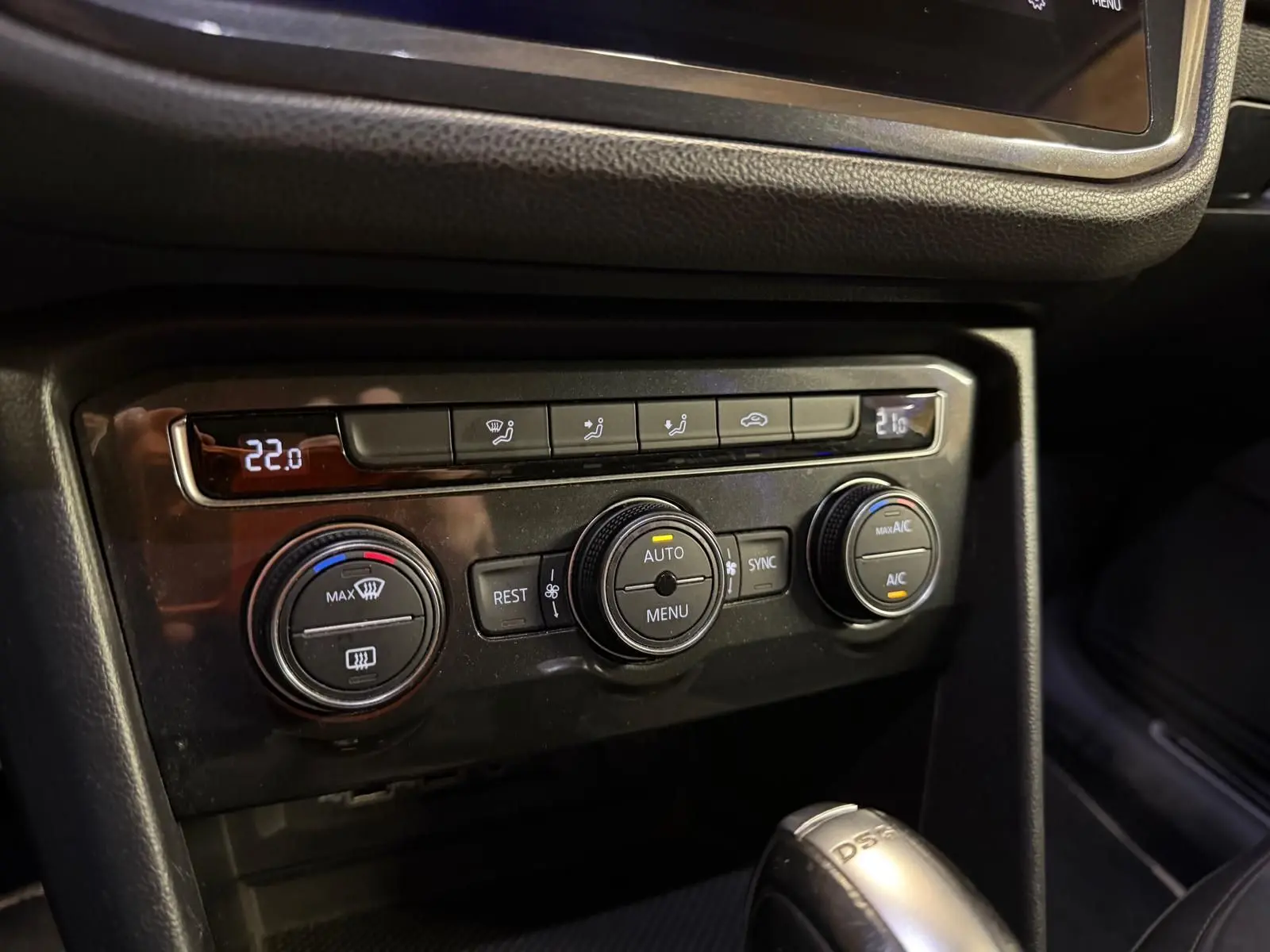 Gros plan sur la console centrale du Volkswagen Tiguan gris, montrant les commandes de climatisation automatique et la boîte automatique DSG.