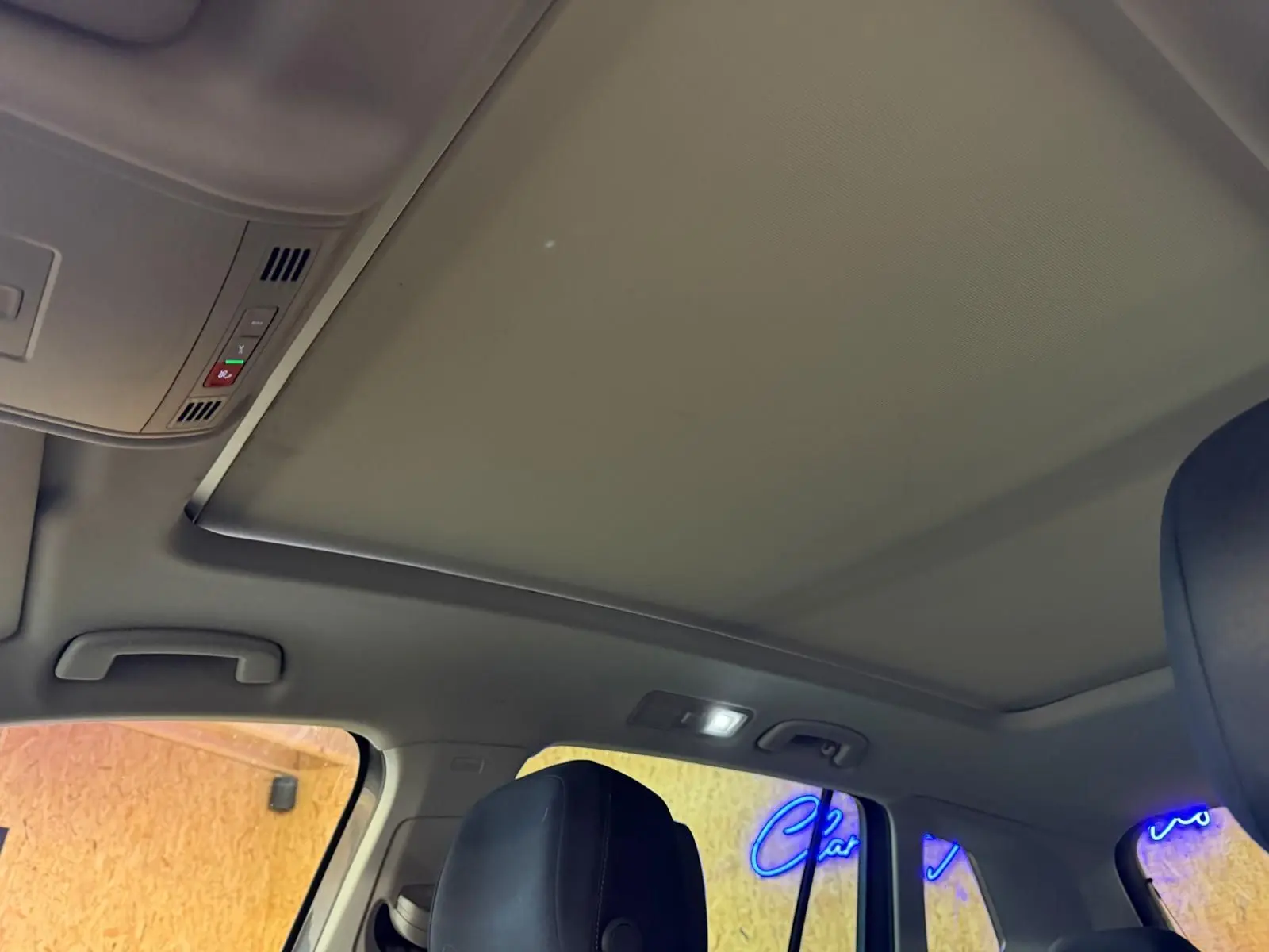 Vue intérieure du toit ouvrant panoramique fermé et des sièges avant en cuir noir du Volkswagen Tiguan gris.