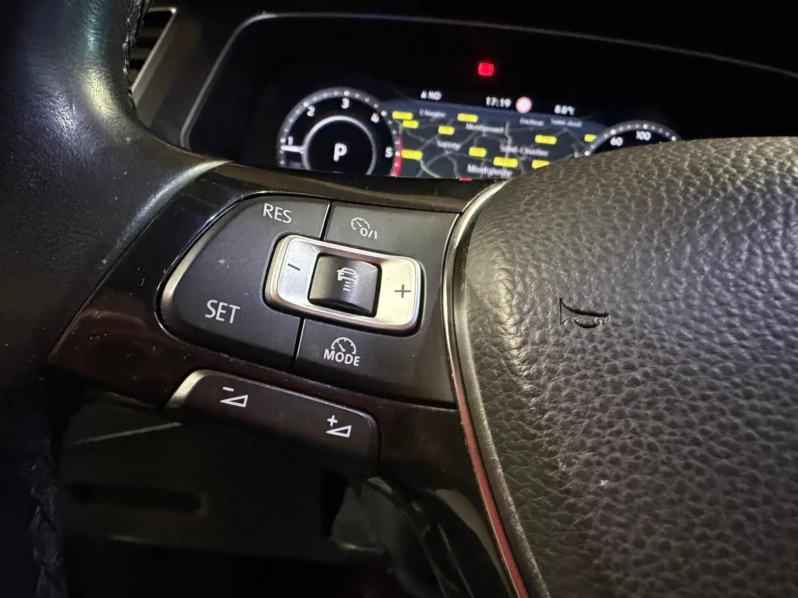 Gros plan sur les commandes du régulateur de vitesse au volant cuir du Volkswagen Tiguan 2018, tableau de bord en arrière-plan.