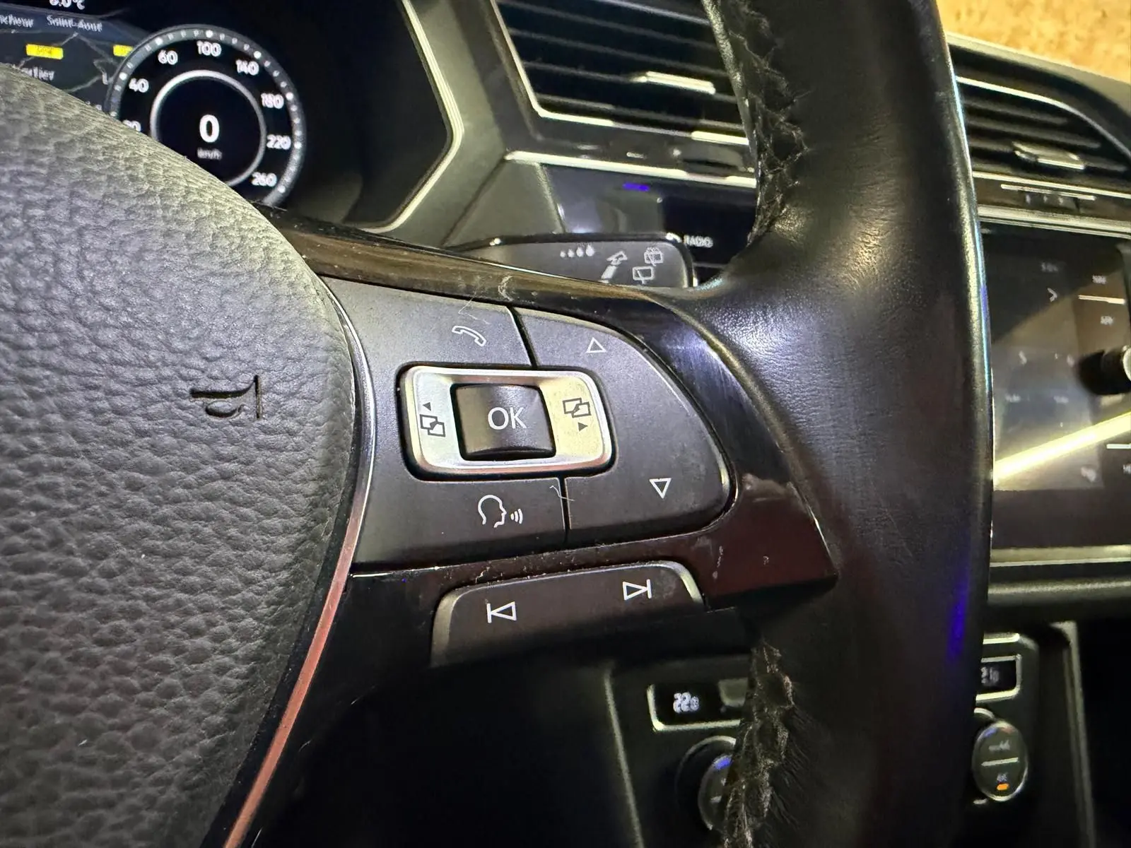 Gros plan sur le volant cuir noir du Volkswagen Tiguan 2018 avec commandes multifonctions et tableau de bord numérique.