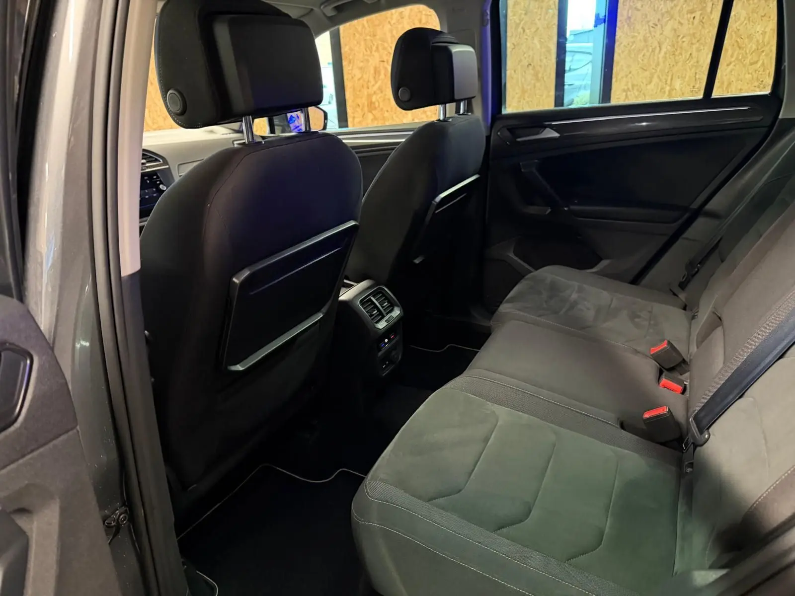 Vue intérieure arrière du Volkswagen Tiguan gris, montrant la banquette arrière en tissu et les dossiers des sièges avant.