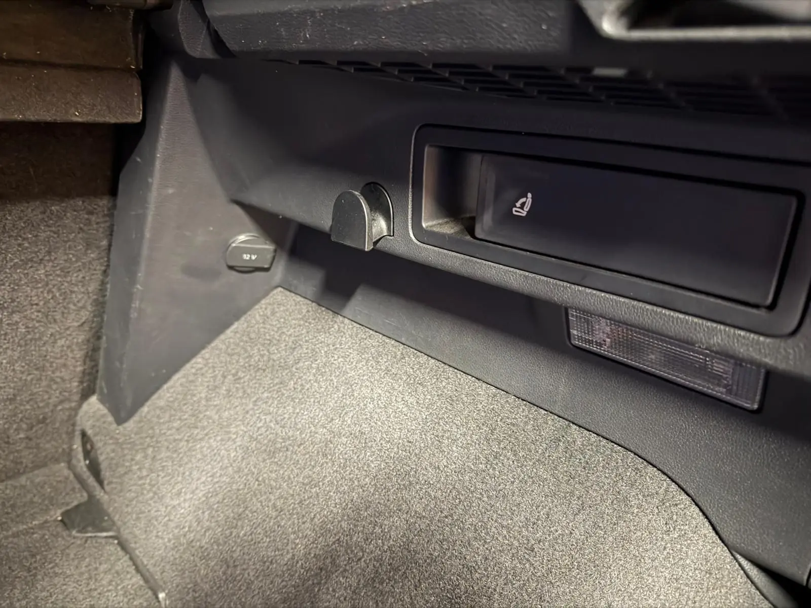 Détail de la console centrale côté passager du Volkswagen Tiguan gris, avec prise 12V et rangement intégré.
