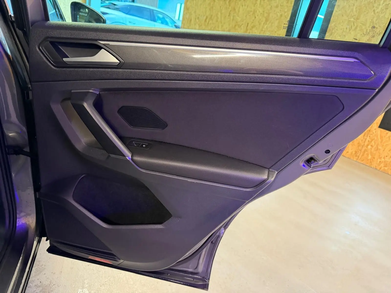 Vue intérieure de la porte arrière droite gris Tungstène du Volkswagen Tiguan 2018 avec accoudoir et commande de vitre électrique.