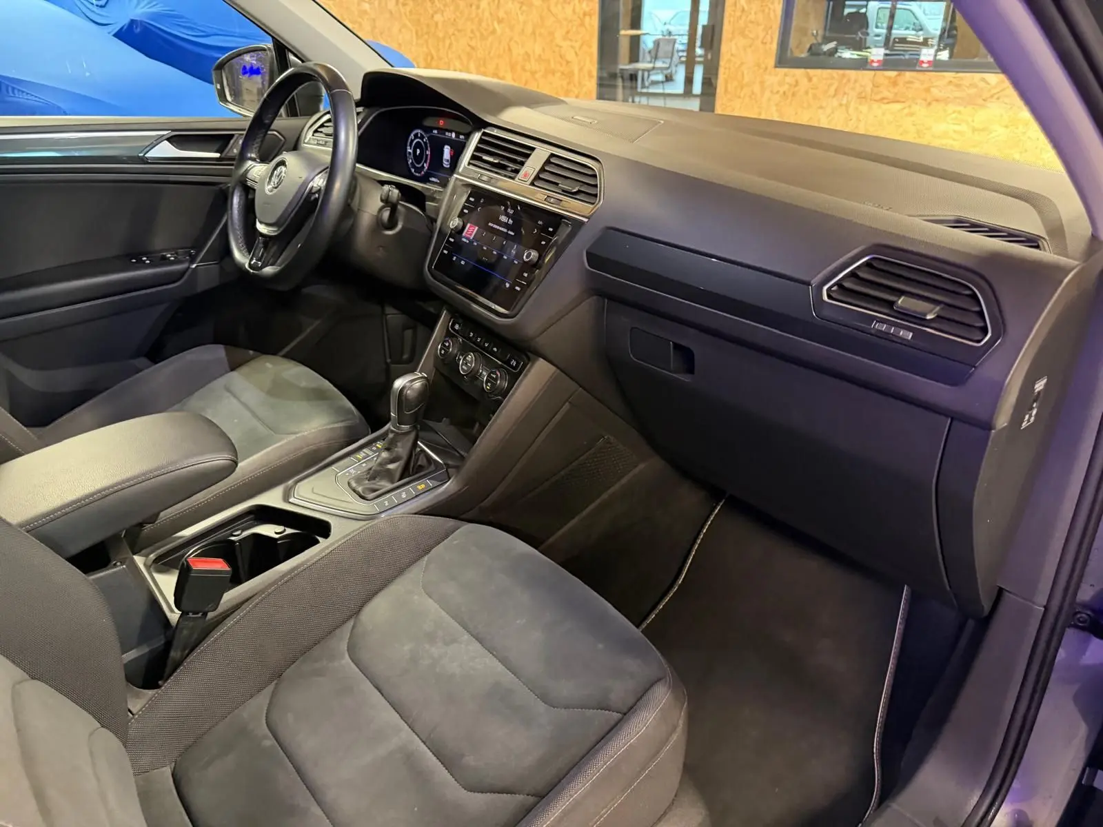 Vue intérieure côté passager du Volkswagen Tiguan 2018, montrant sièges sport gris et tableau de bord moderne avec écran tactile.