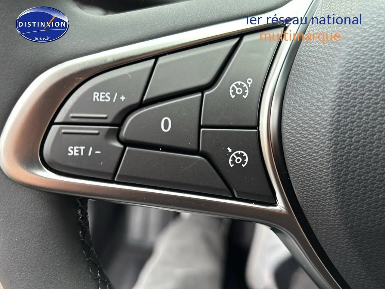 Gros plan sur les commandes du régulateur de vitesse au volant d'une Renault Clio V noire, intérieur moderne.