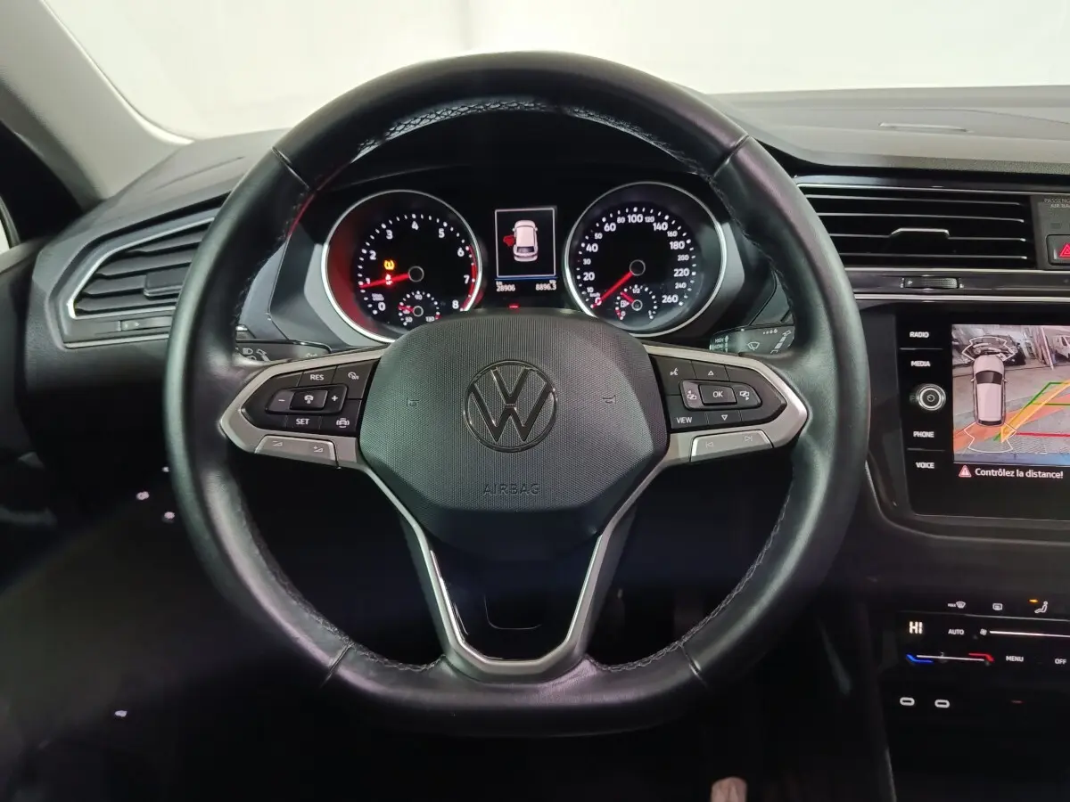 Vue rapprochée du volant cuir multifonctions noir du Volkswagen Tiguan 2021 avec tableau de bord et écran tactile.