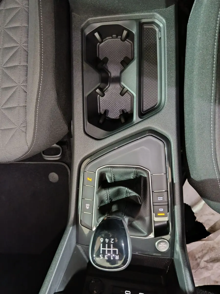 Vue plongeante sur le levier de vitesses manuel et les porte-gobelets du Volkswagen Tiguan bleu, intérieur noir.