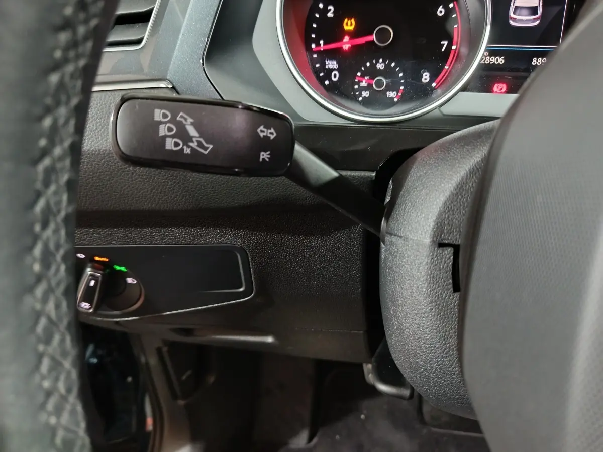 Gros plan sur le commodo gauche du volant noir d’un Volkswagen Tiguan 1.5 TSI 2021, avec tableau de bord partiel visible.