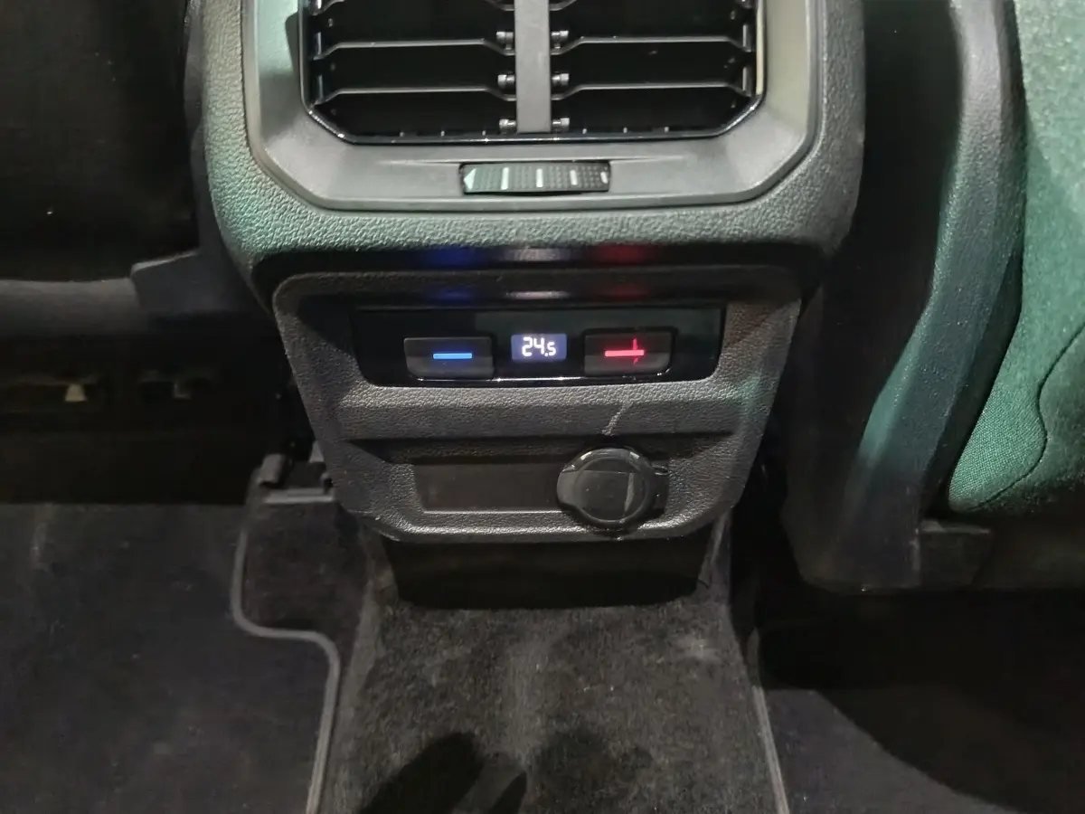 Gros plan sur la console arrière du Volkswagen Tiguan bleu, affichant la climatisation digitale à 24,5°C et une prise 12V.