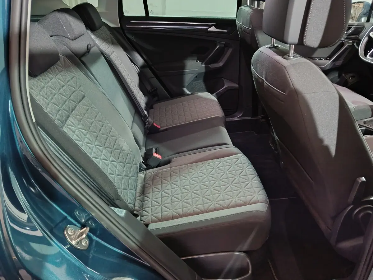 Vue intérieure côté arrière droit du Volkswagen Tiguan bleu 2021, montrant les sièges arrière en tissu gris à motif géométrique.