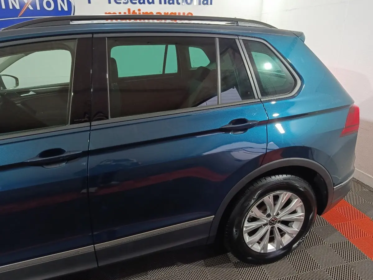Vue latérale droite d'un Volkswagen Tiguan bleu métallisé, mettant en valeur les jantes alliage et les vitres teintées.