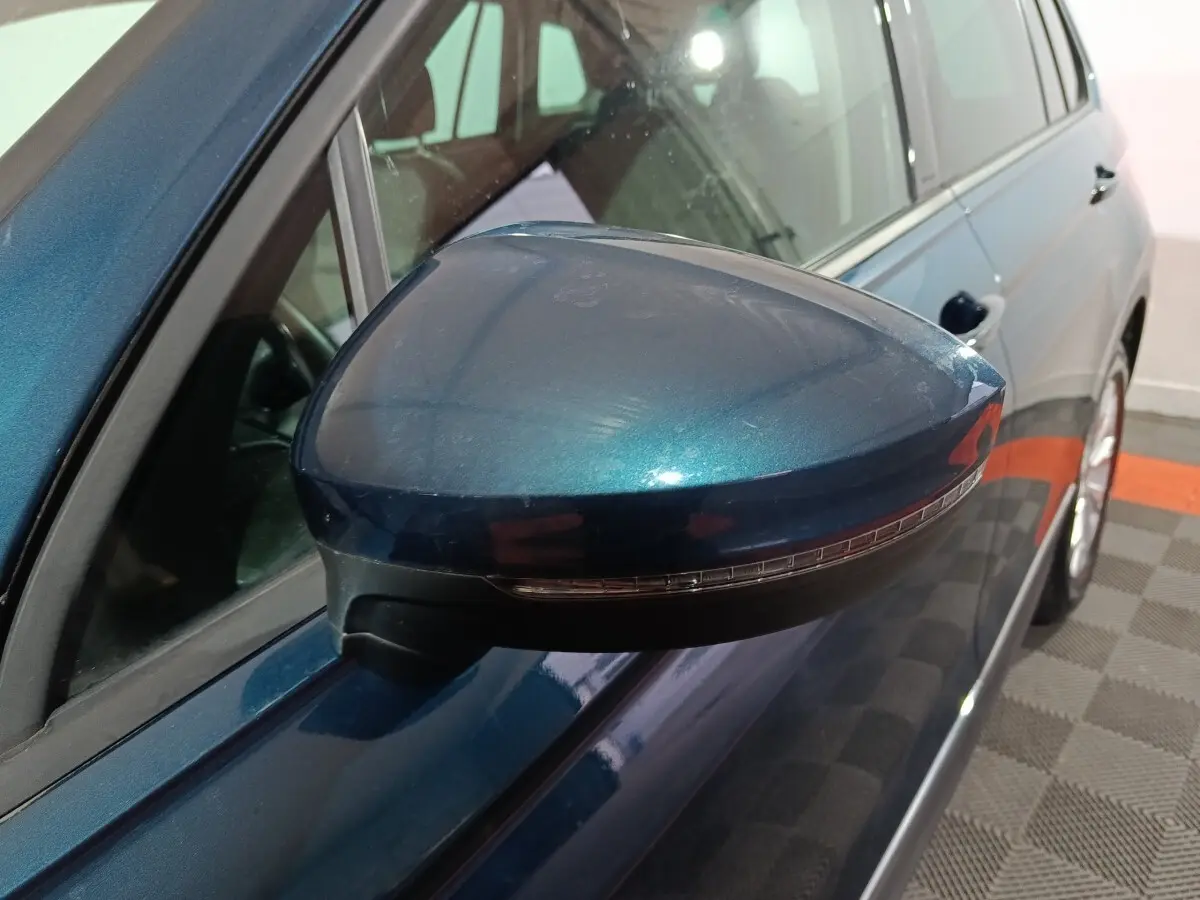 Rétroviseur côté gauche bleu métallisé du Volkswagen Tiguan 2021, avec clignotant intégré, vue rapprochée en intérieur.