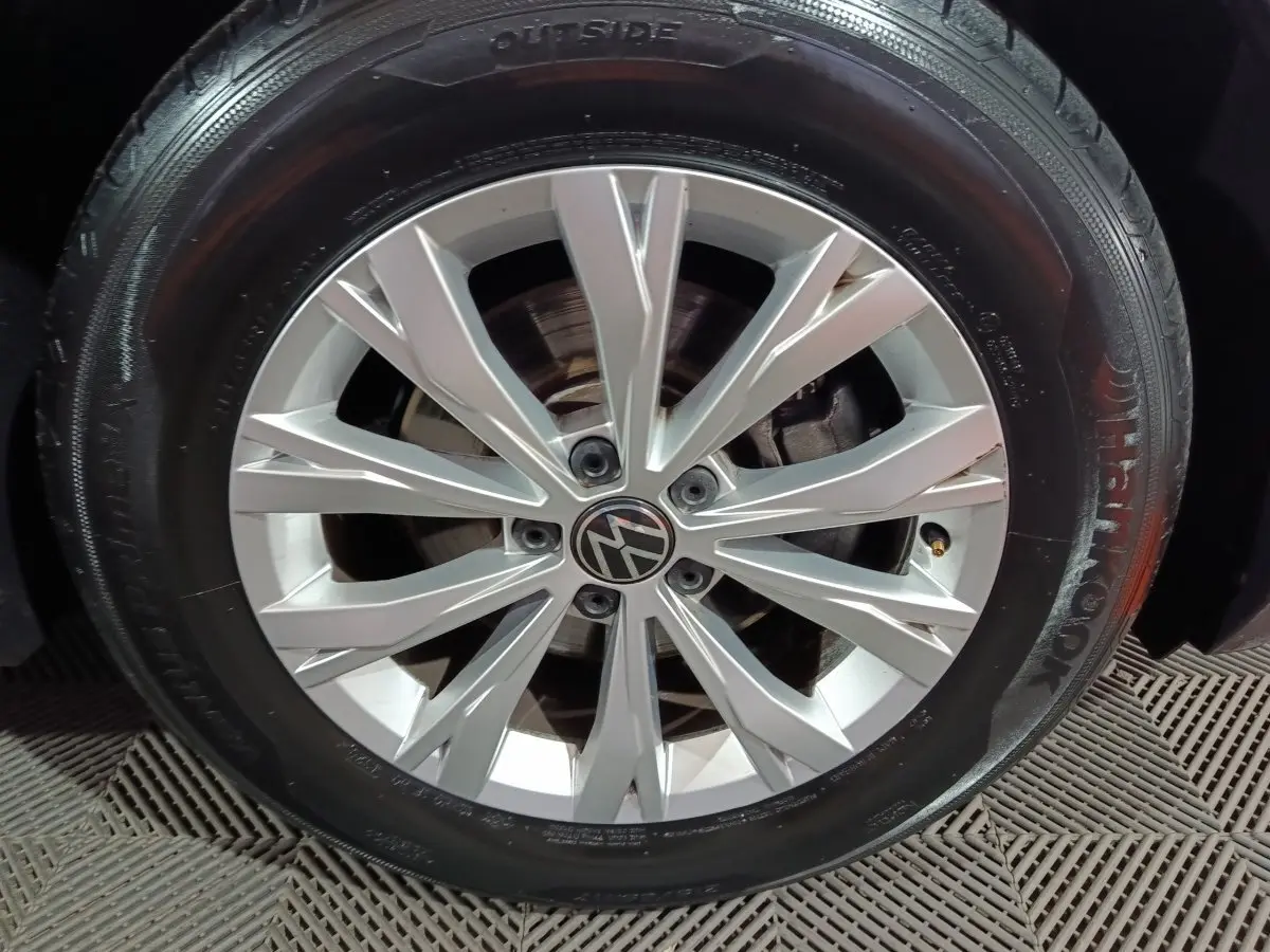 Gros plan sur la jante alliage argentée avec logo Volkswagen, montée sur pneu Hankook noir du Tiguan bleu.