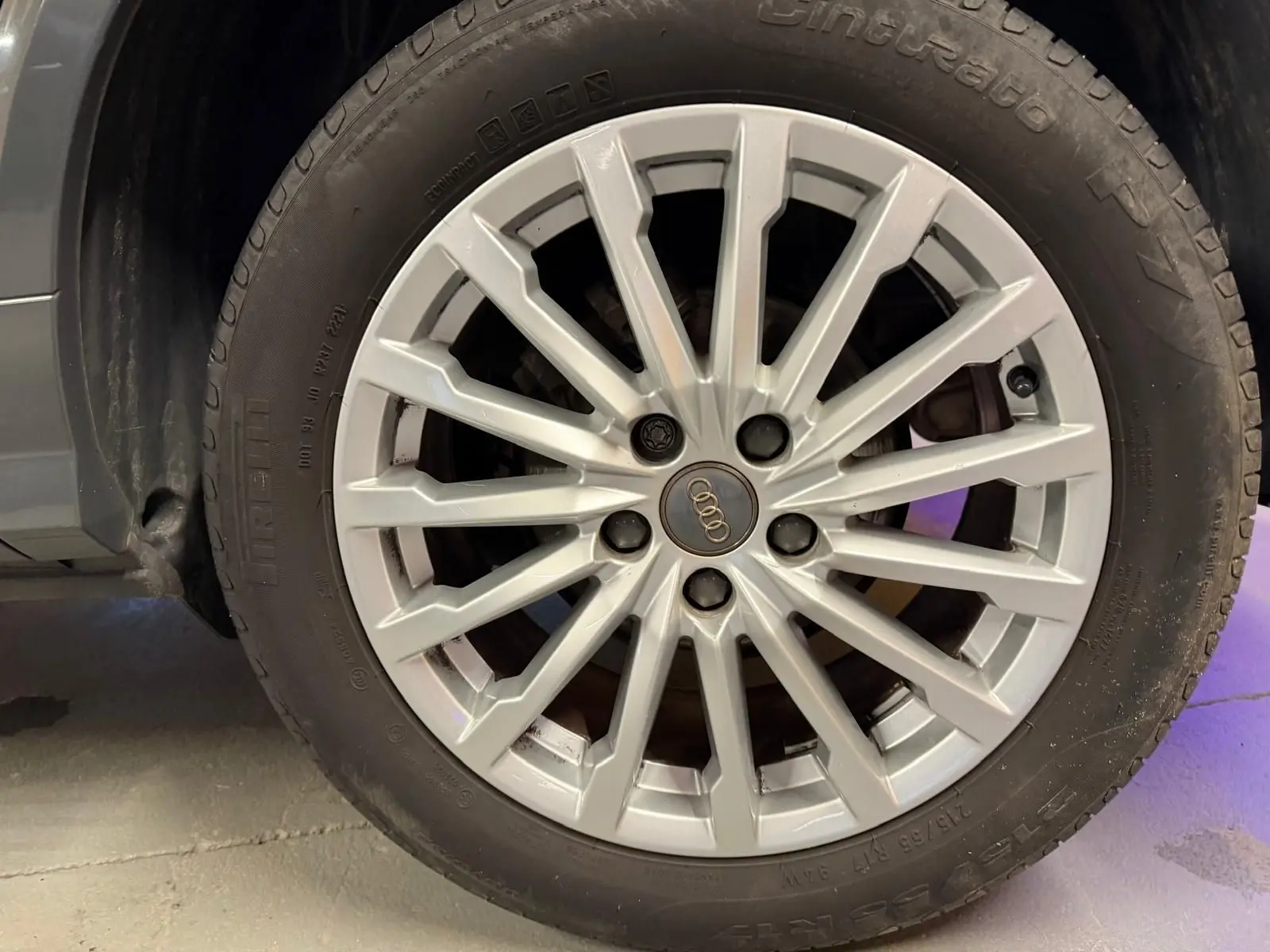 Gros plan sur la jante alu argentée d'une Audi Q2 gris, mettant en valeur le logo Audi au centre.