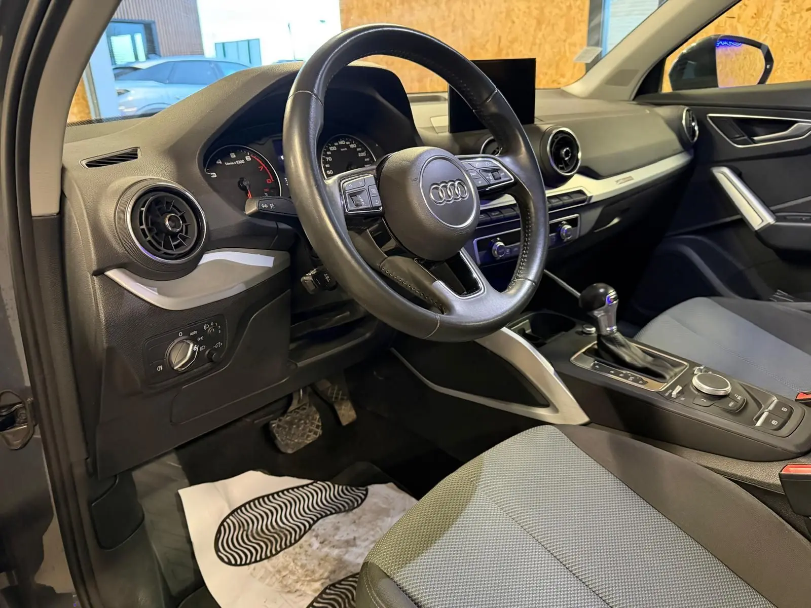 Vue intérieure côté conducteur de l'Audi Q2 2018, volant cuir multifonctions et console centrale avec boîte auto.